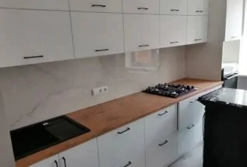 Белая кухня со столешницей цвета натурального дерева и черные ручки